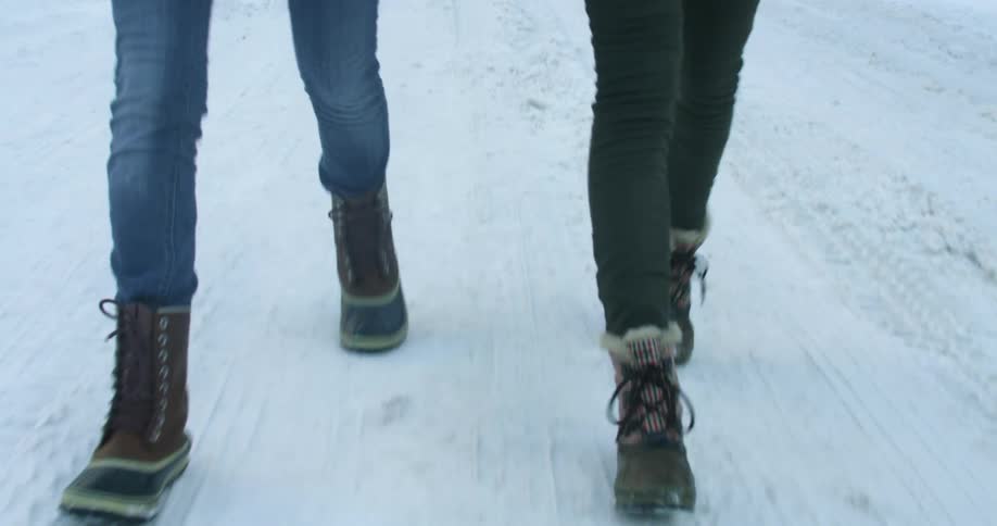 Close up of two peoples legs walking in the snow
