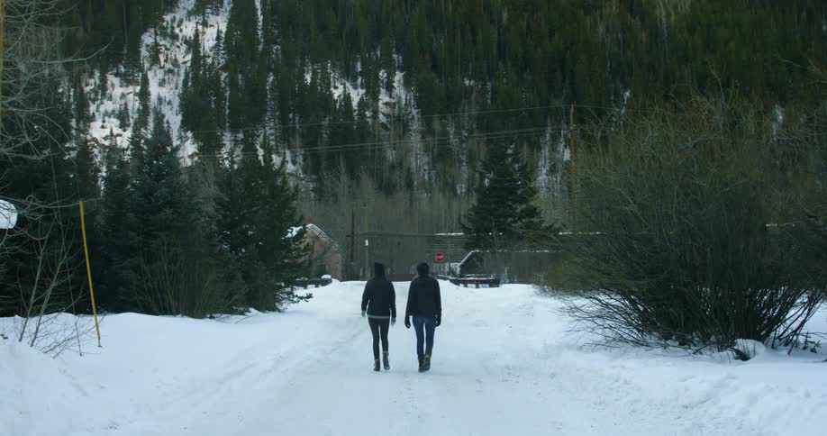 Two people walk in the snow together