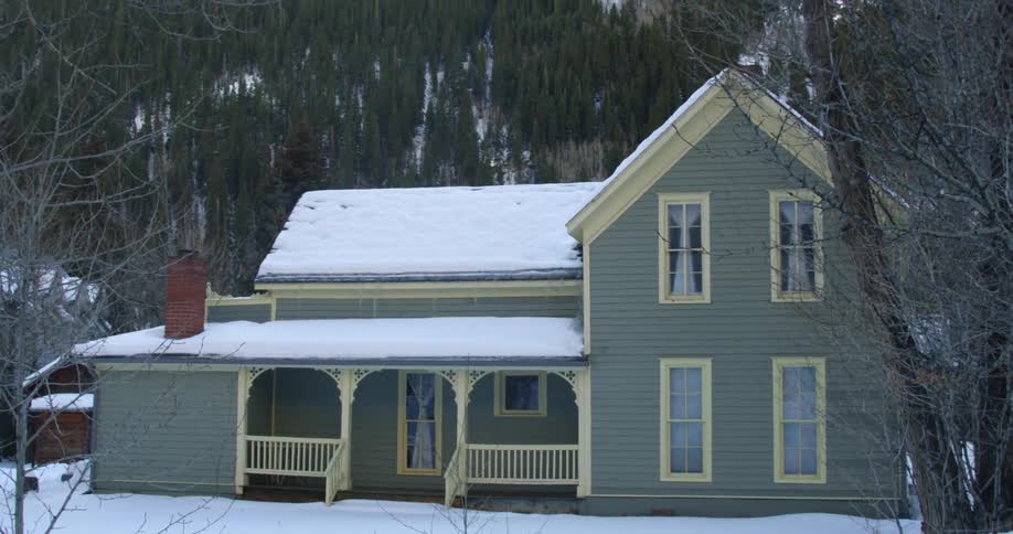 A house has a hillside behind it covered with trees