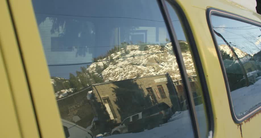 Windows of a vehicle reflect a building across street