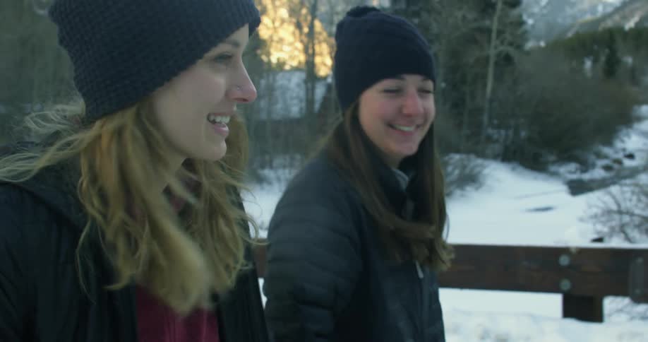 Two women are walking outside and smile at each other