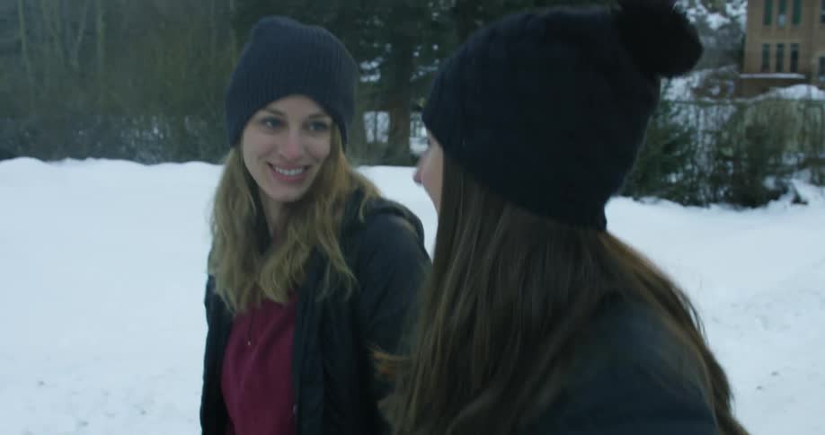 Two women walk outside with snow around them