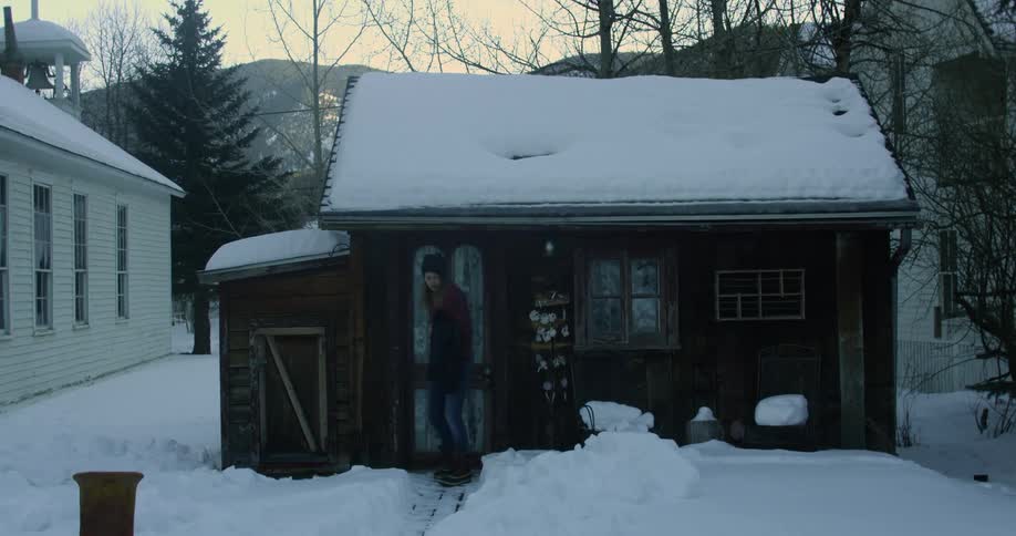 A woman leaves a home covered with snow