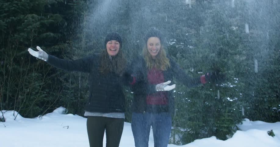 Two women throw snow in the air