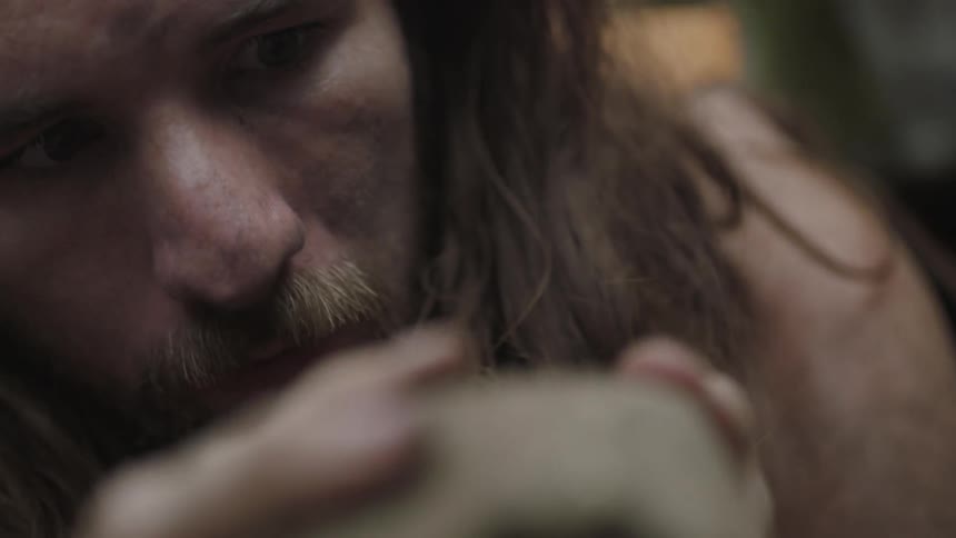 A man holds and examines a rock