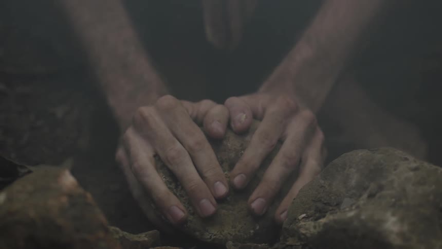 A man picks up a rock from the ground