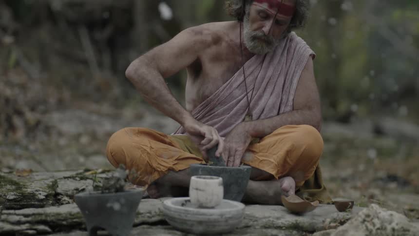 A man grinds a mortar and pestle outside