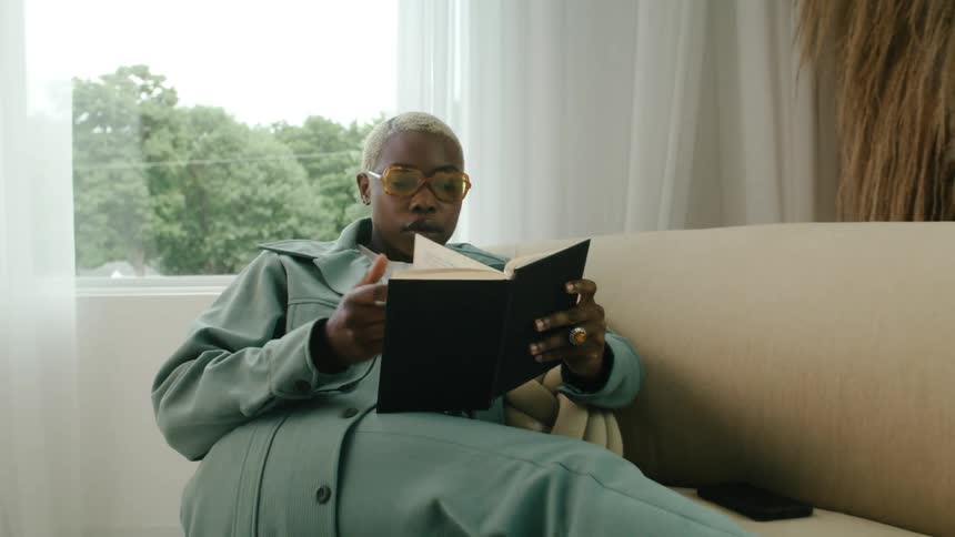 A woman is reading a book inside of her house