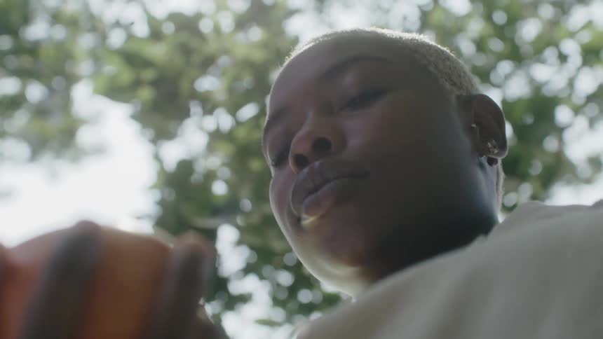 A woman is standing outdoors and holding an object