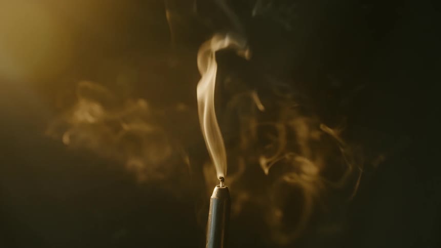 A puff of air blows out a candle flame causing smoke to swirl and float