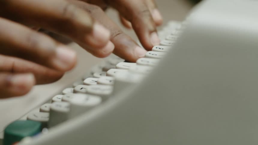 Hands and fingers are typing on a typewriter