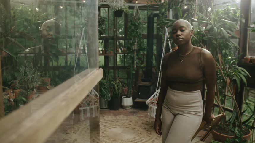A woman is standing in a green house with plants
