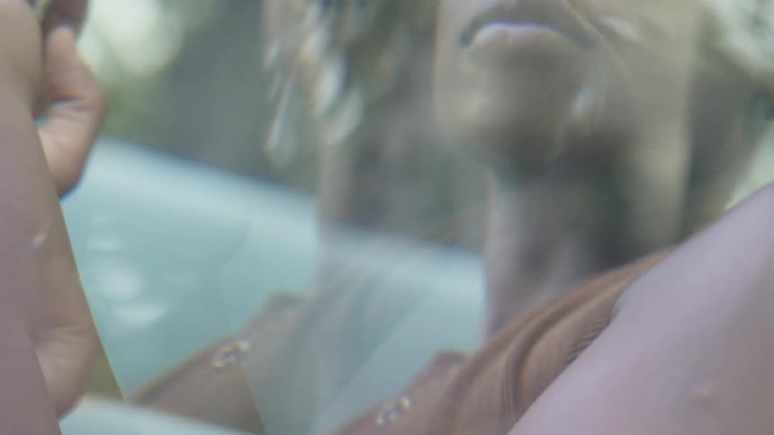 A woman is standing outside and moving her hands as she dances