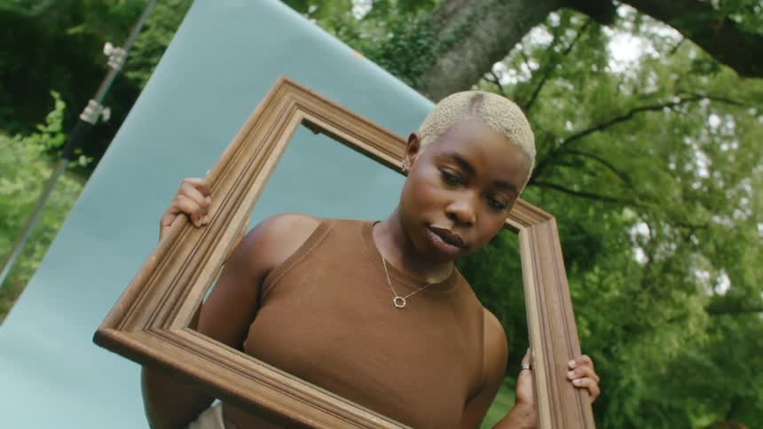 A woman is holding a picture frame over her head