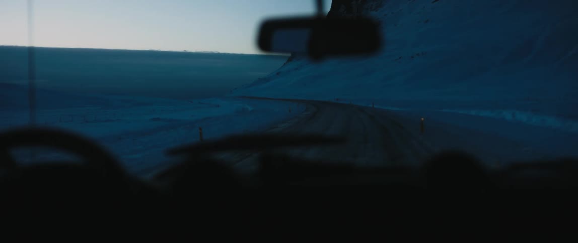 A view of a truck driving up a mountain with snow