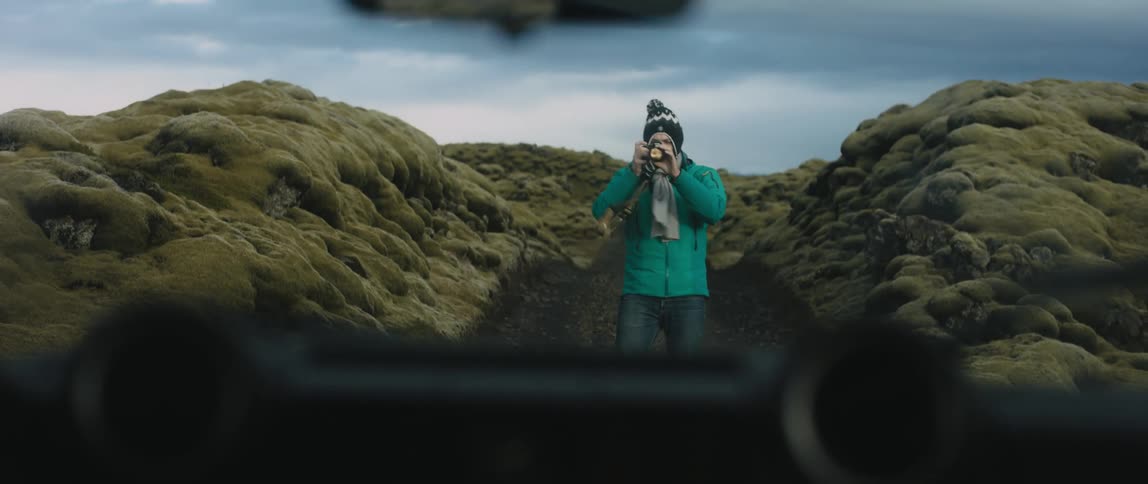 A man stands outside a canyon and takes photos of his vehicle