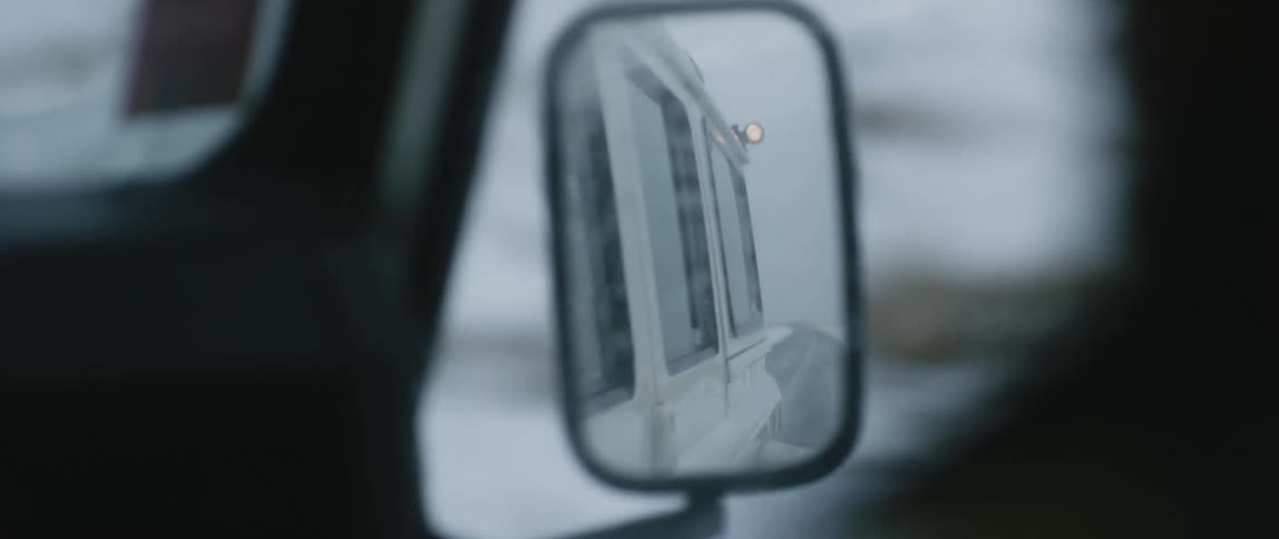 A car is driving in a rural area in winter
