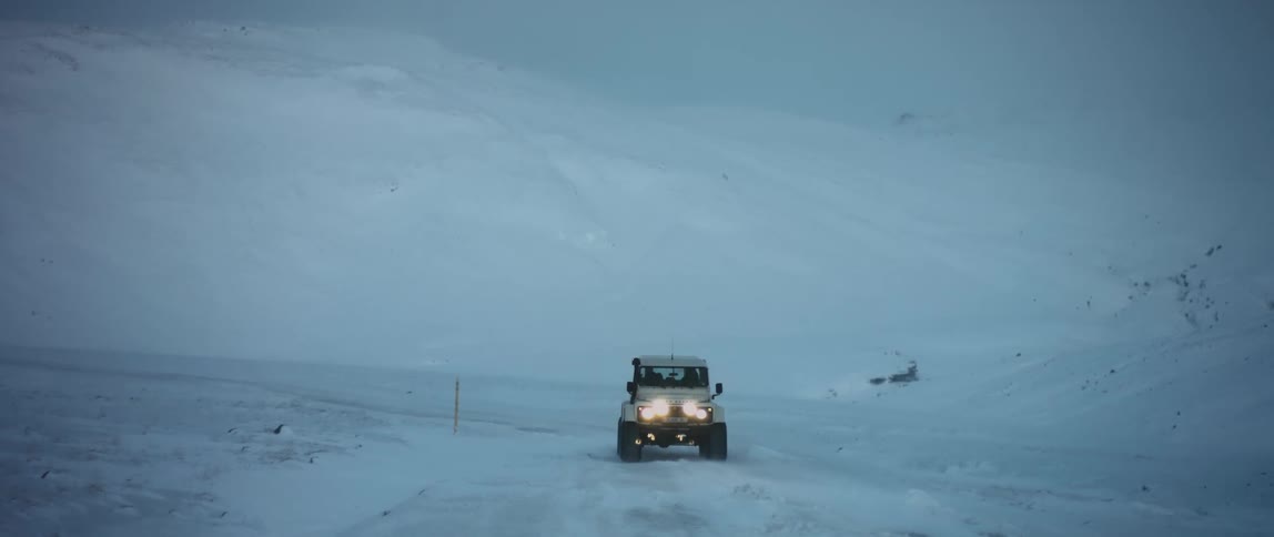 A car is driving through an arctic area with snow