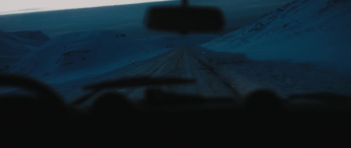 A vehicle is driving down the snow covered road