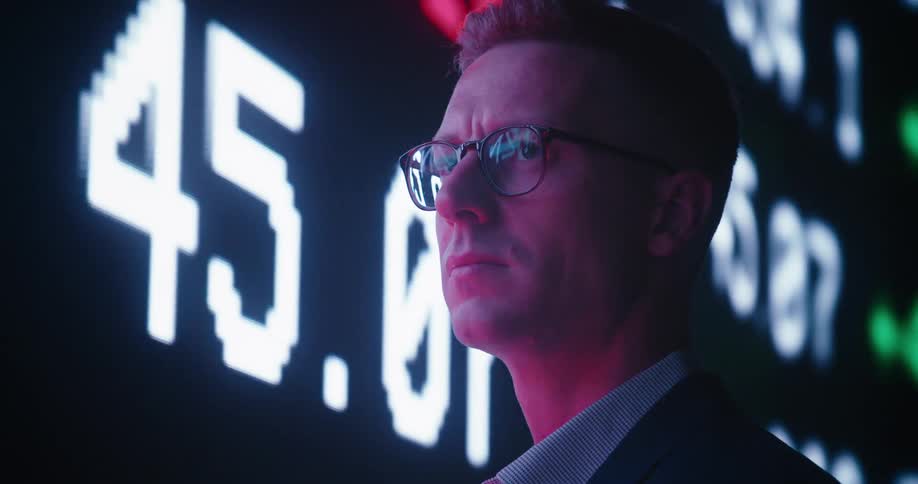 A man is standing in front of a digital stock ticker