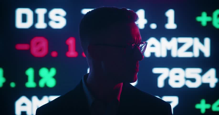 A man standing turning his head left and right as stock prices scroll behind him