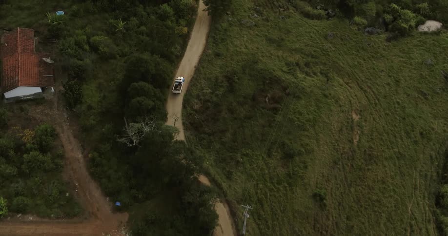 A truck is driving on a dirt road in the mountains next to a river