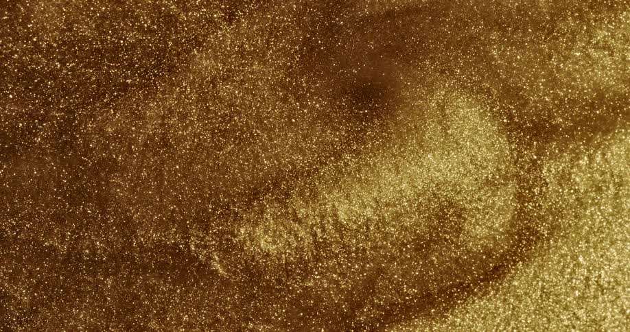 Golden grains of sand surges and swirls