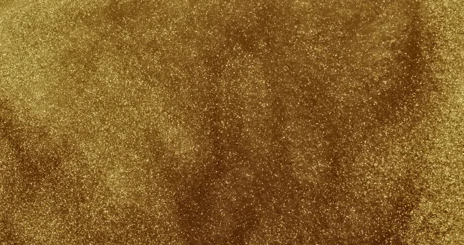 A golden organic liquid substance moves as if it is alive and sparkles in the light