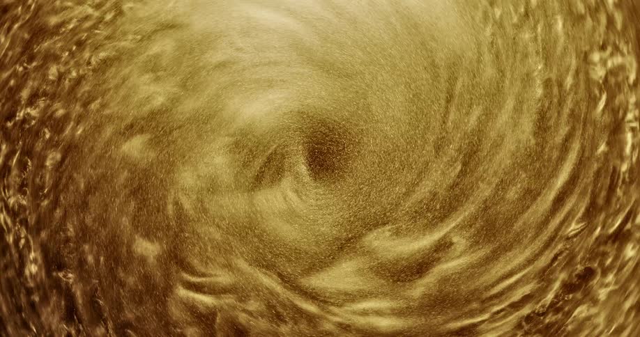 A pool of golden organic liquid sparkles as it swirls into a vortex