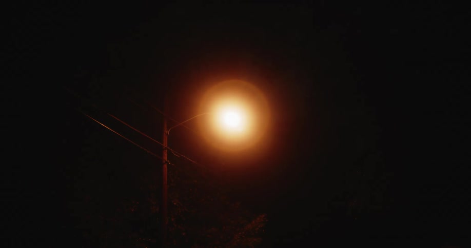 The orange light from a street lamp glows in a circle against the night sky