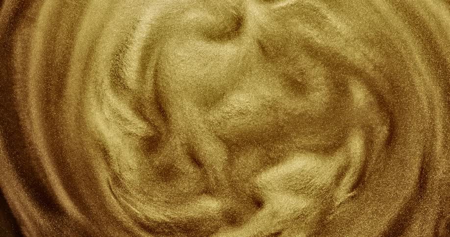 Gold smooth velvety liquid very slowly swirls around at a highly magnified distance