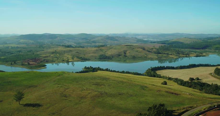 Sloping pasture sits across reflective river from hilly terrain