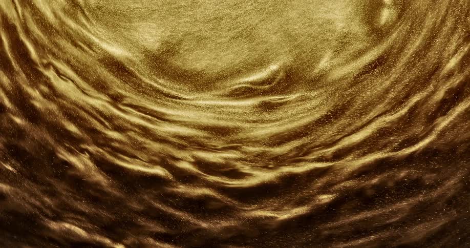 Gold glittery liquid is shown highly magnified swirling around fast and then slows down