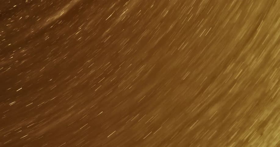 Golden glitter swirls around in a circular manner very rapidly creating a beautiful scene