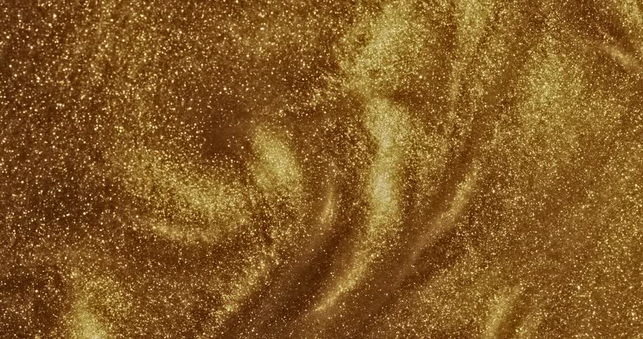 A glittery gold liquid substance sparkles as it ripples and moves