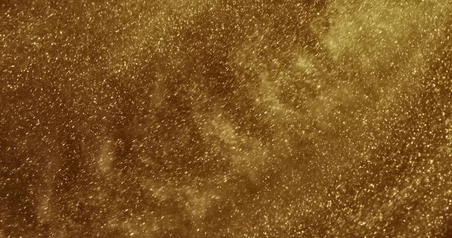 Gold sand particles flow forming cloudy mass