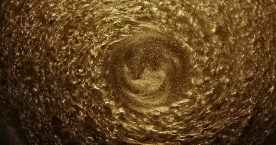 A gold substance swirls into itself and creates a ripple