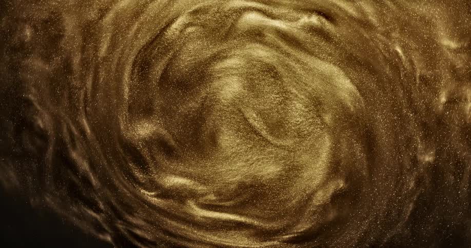 Golden grains of glitter spinning in a circular wave pattern