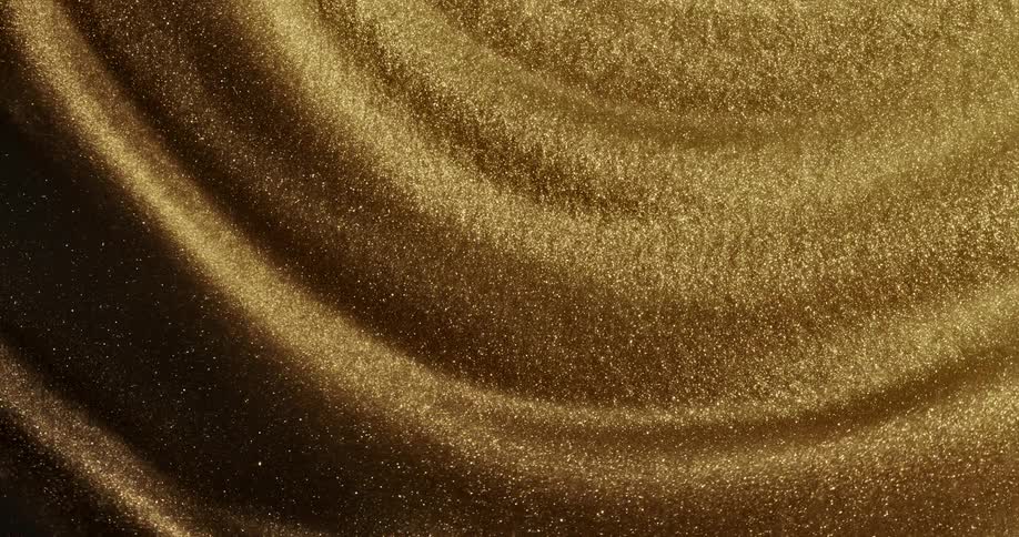 A golden liquid turns and sparkles in a swirl