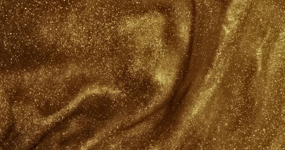 A gold organic liquid substance ripples and sparkles as it moves