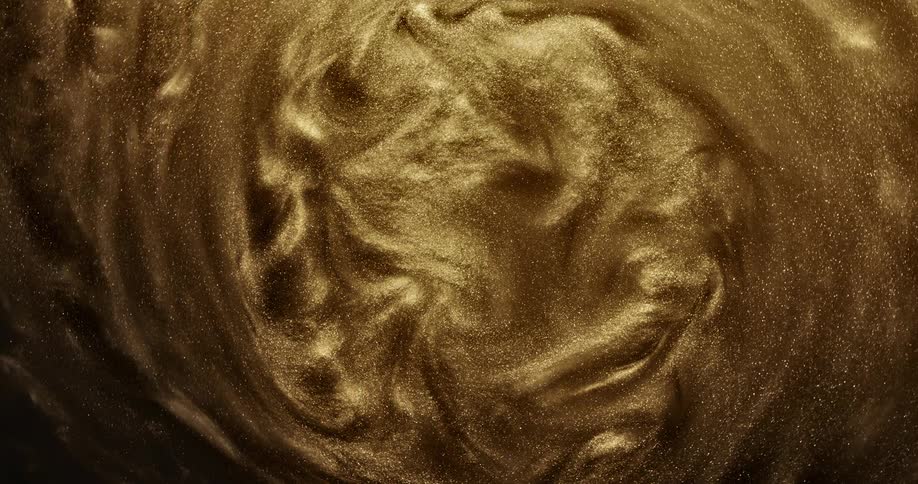 A pool of golden organic liquid sparkles as it swirls into a vortex