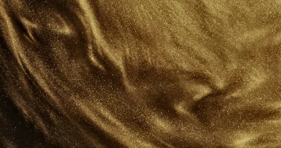 Gold sand flows forming swirls as it moves slowly then a cloudy mass as it moves quickly