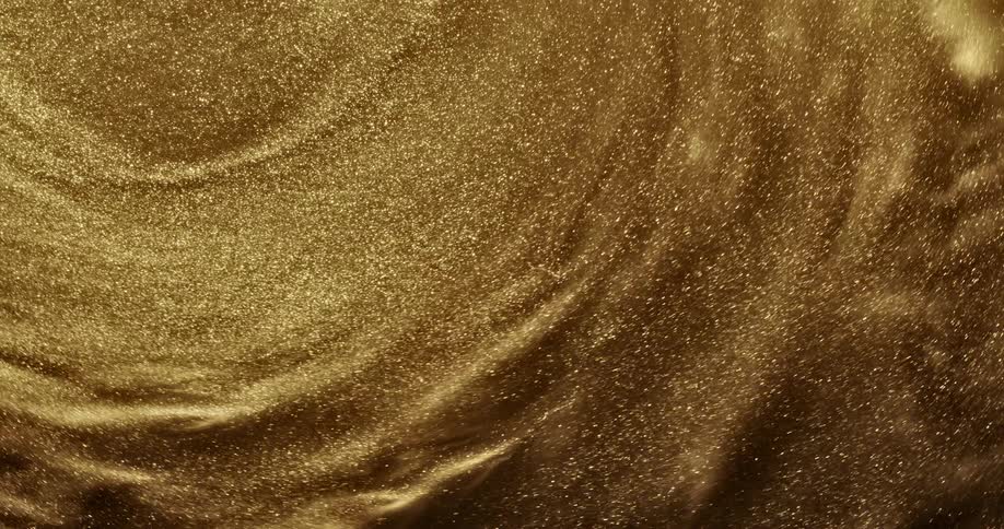 Metallic sand particles shimmer as they spin and flow