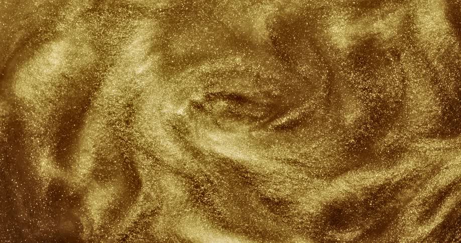 Golden glitter shimmers as it swirls around and creates mesmerizing ripples