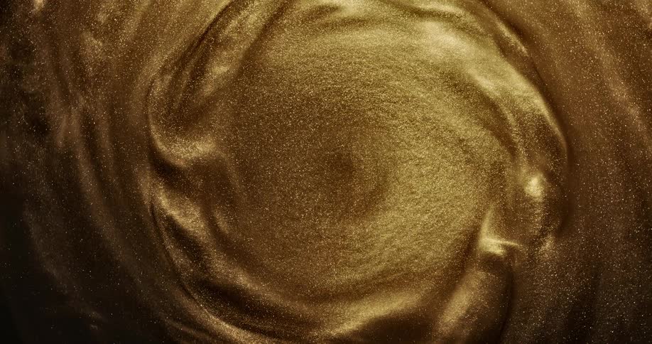 Golden glitter shimmers as it swirls around and creates a mesmerizing pattern