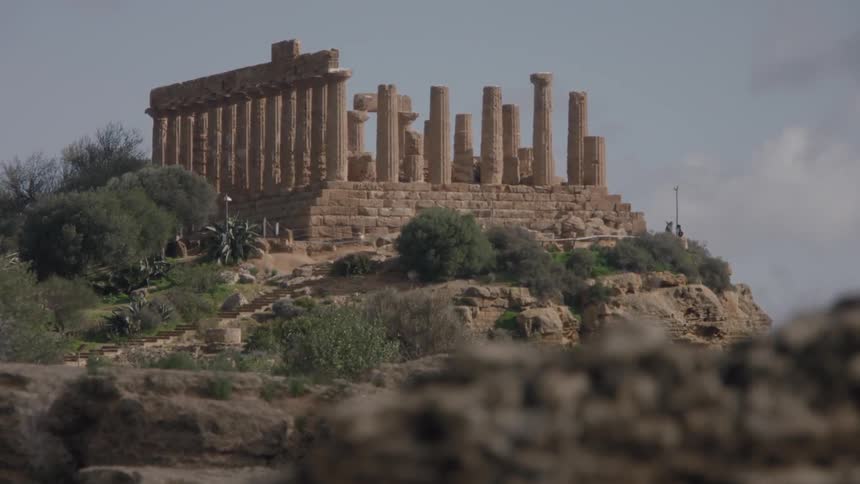 Ruins sit atop a hill with shrubs