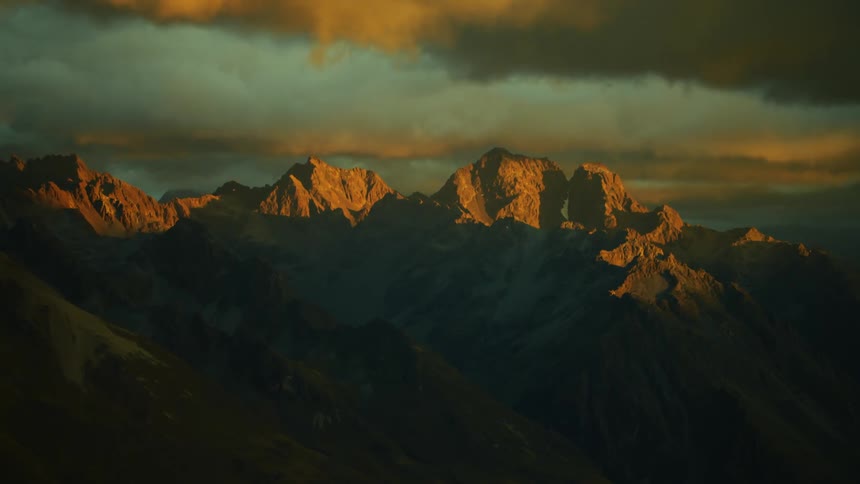 Thick clouds pass over a mountain ridge in the evening
