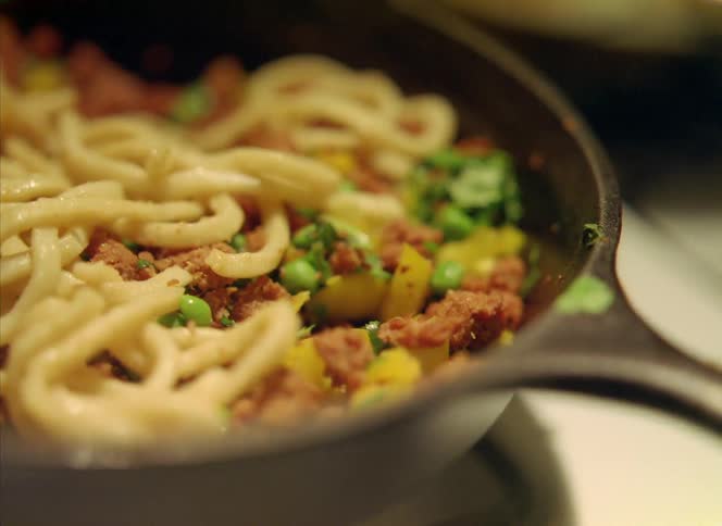 A noodle dish being prepared in a metal pan