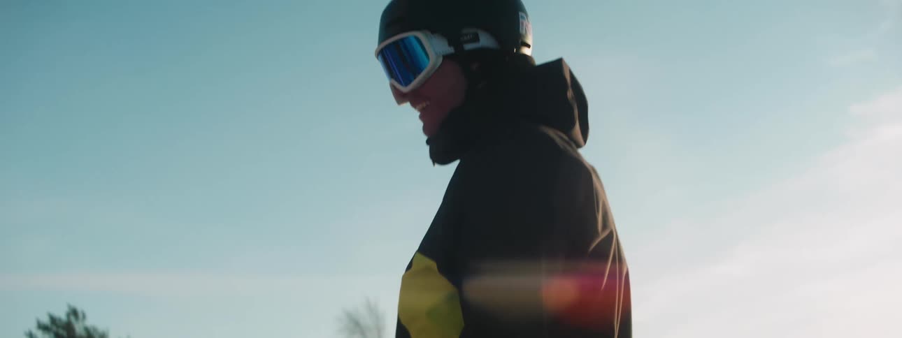 A man and woman chat outside wearing ski goggles