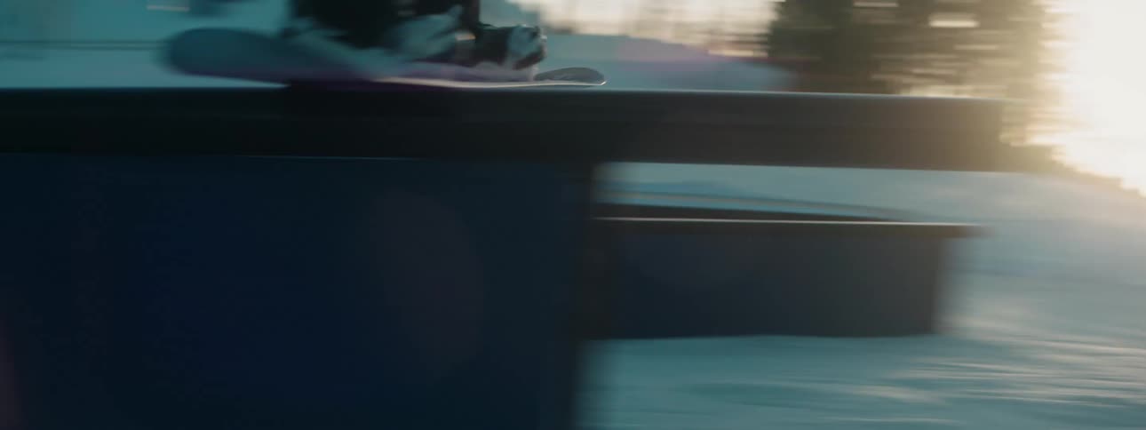 A person is snowboarding down a mountain at dusk